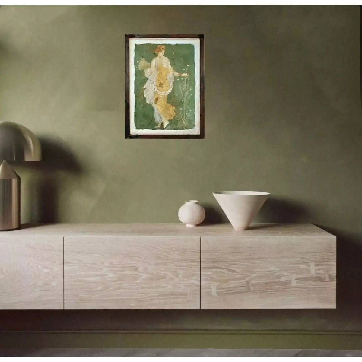 Affresco di Flora di Stabiae in cornice, appeso a una parete verde sopra un mobile chiaro con vasi.