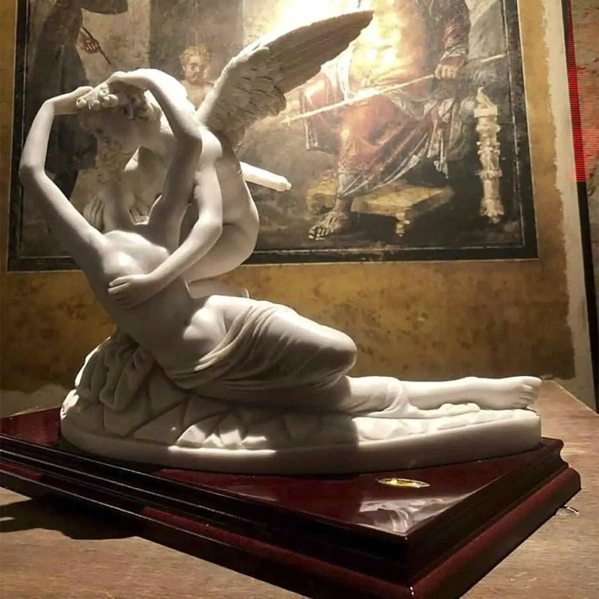 Amore e Psiche in marmo ricomposto su base in legno, davanti a un quadro