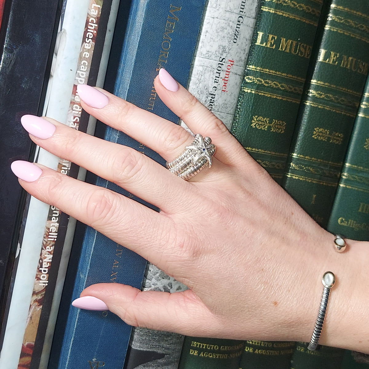 Anello a sei giri con stella marina, indossato sulla mano con un bracciale aperto al polso