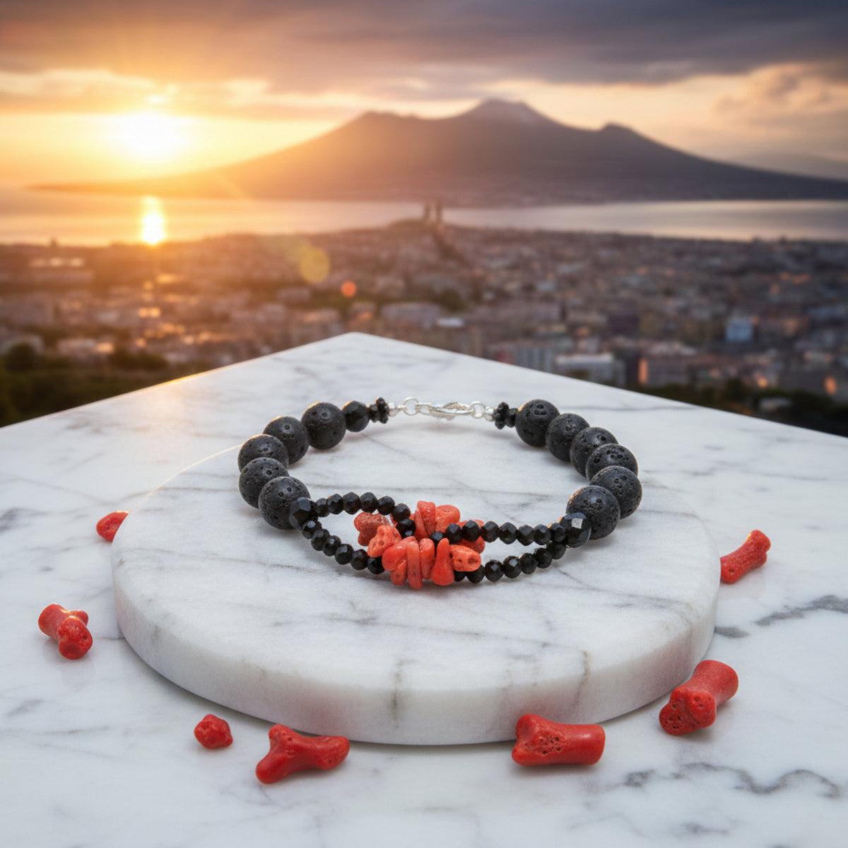 Bracciale con scaglie di corallo rosso, pietra lavica e onice su un supporto chiaro, con mare e montagna al tramonto sullo sfondo