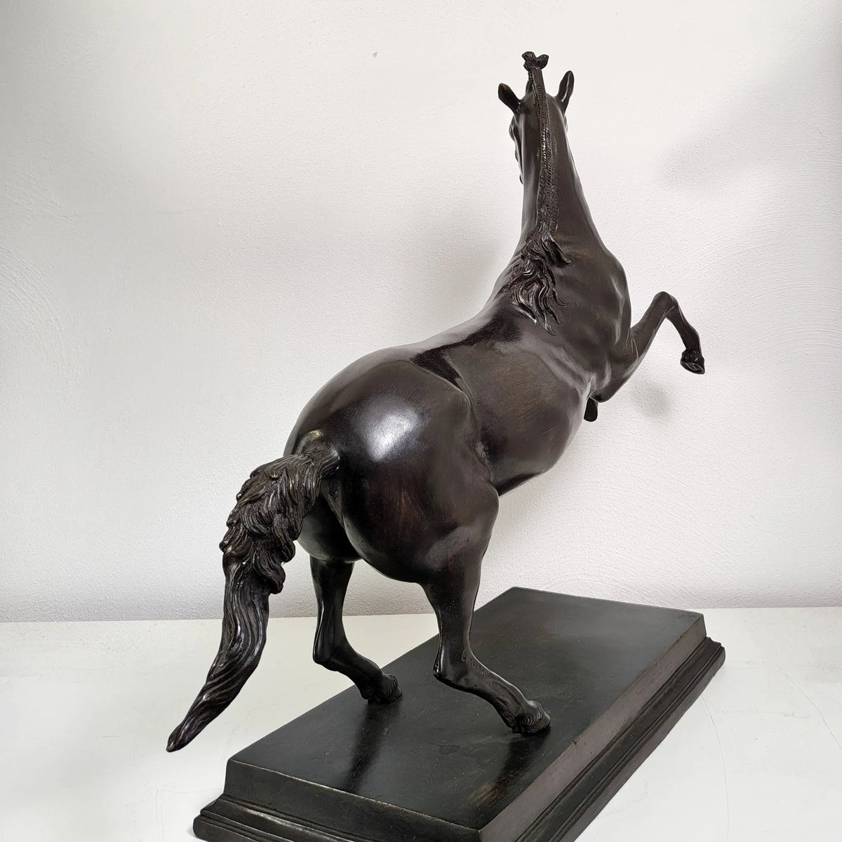 Scultura di Bucefalo in bronzo vista da dietro, con coda e criniera scolpite su base rettangolare.
