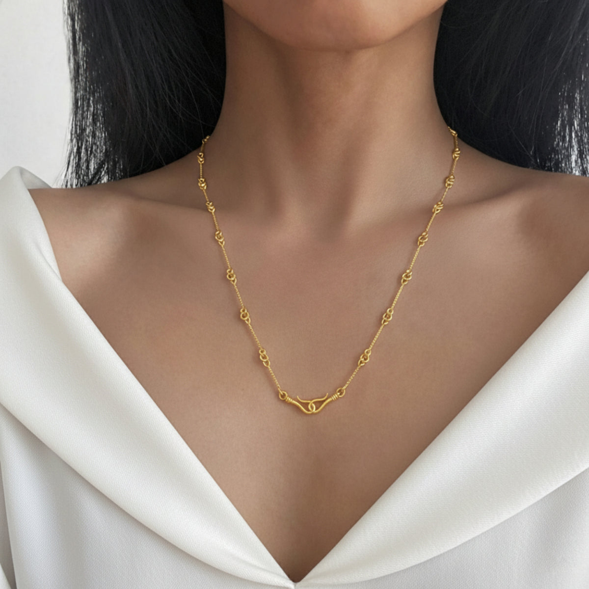 Collana con ami di Pompei dorata indossata su una maglia bianca