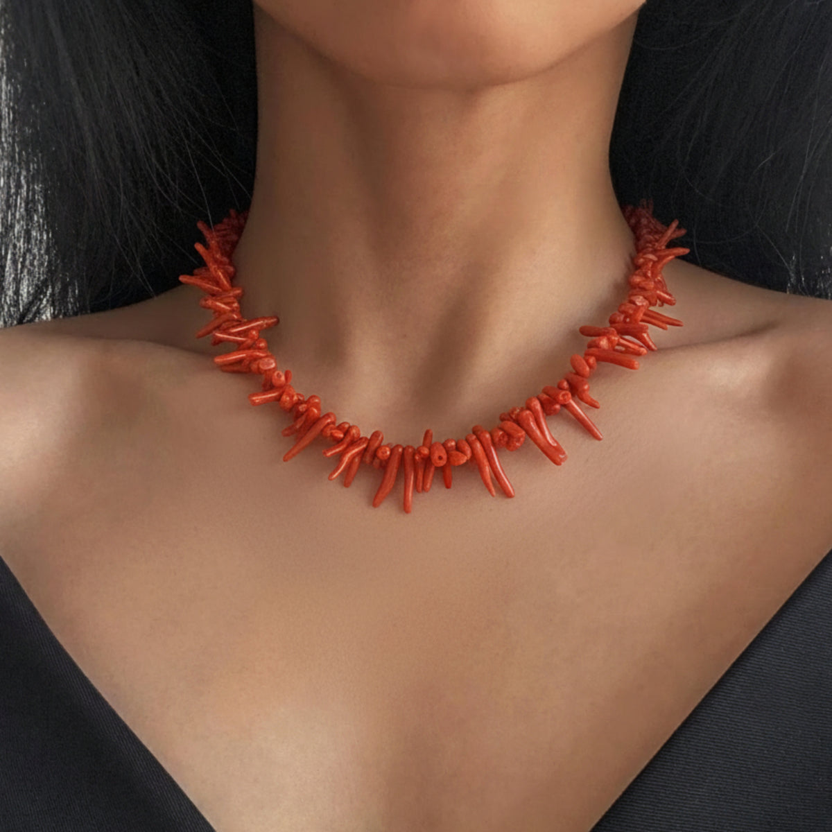Collana con corni in corallo rosso indossata su un abito nero