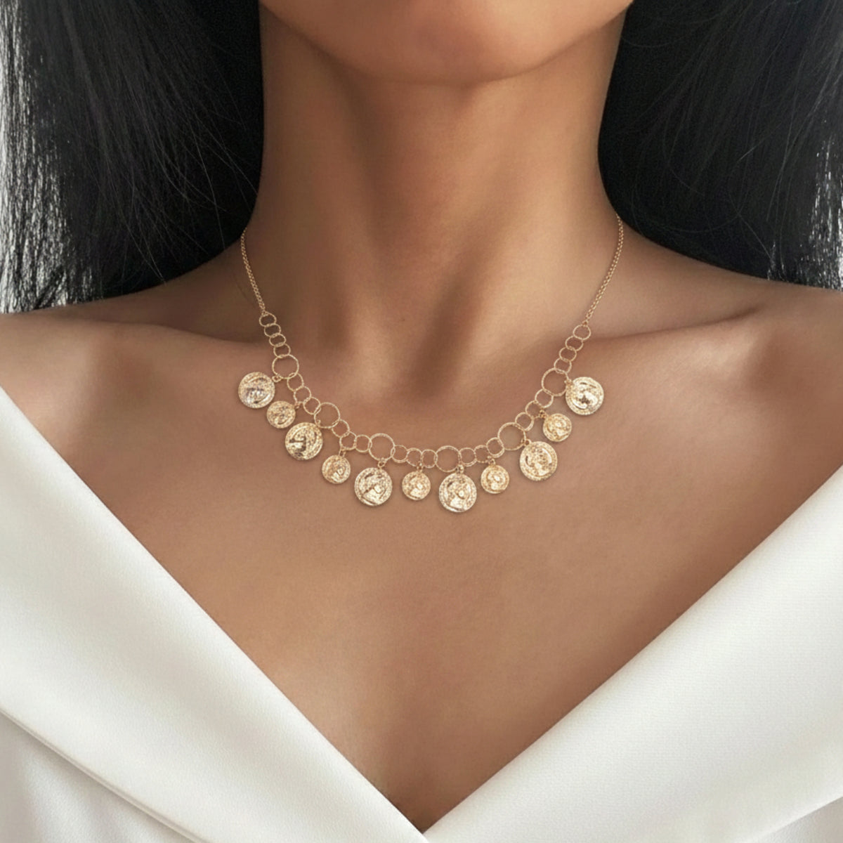 Collana con medagliette pendenti in argento dorato indossata su un abito bianco