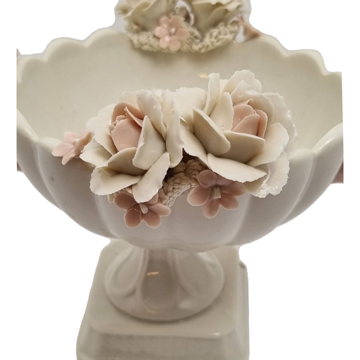 Dettaglio delle rose chiare e dei piccoli fiori rosa sul bordo della coppa in porcellana di Capodimonte.