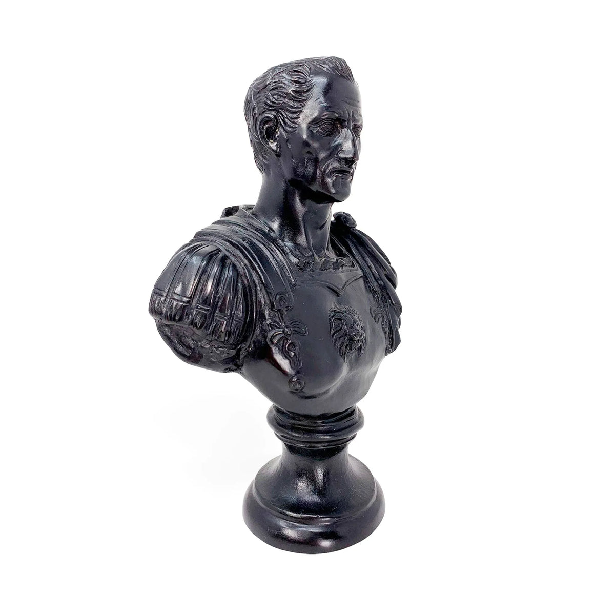 Busto di Giulio Cesare in bronzo con patina nera, visto di tre quarti dal lato opposto su fondo bianco.
