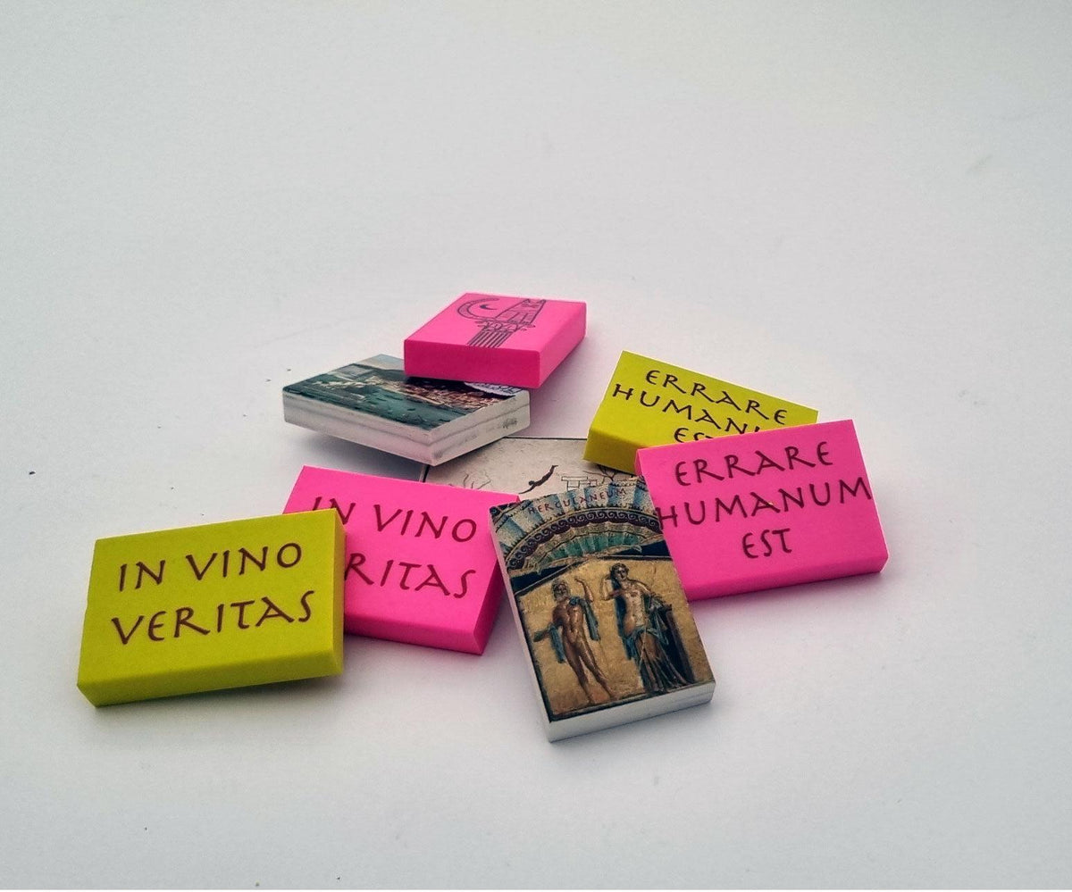 Gomme rosa, gialle e bianche con frasi latine e decorazioni artistiche, disposte in gruppo
