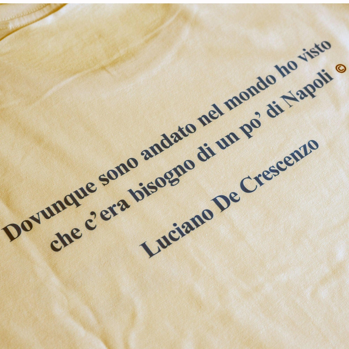 Dettaglio della citazione su Napoli e del nome di Luciano De Crescenzo stampati sulla maglietta chiara