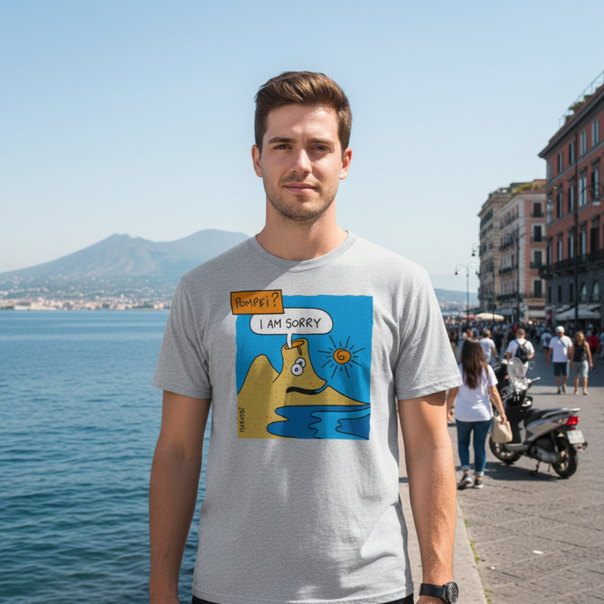 Uomo con maglietta grigia, vulcano illustrato e scritte “Pompei?” e “I Am Sorry”, sul lungomare