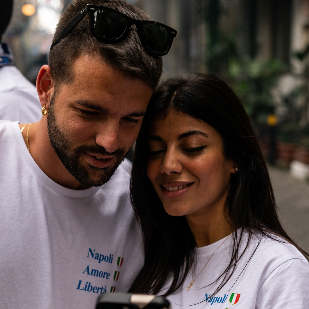 Uomo e donna indossano magliette bianche con scritte “Napoli Amore Libertà” e scudetti tricolori