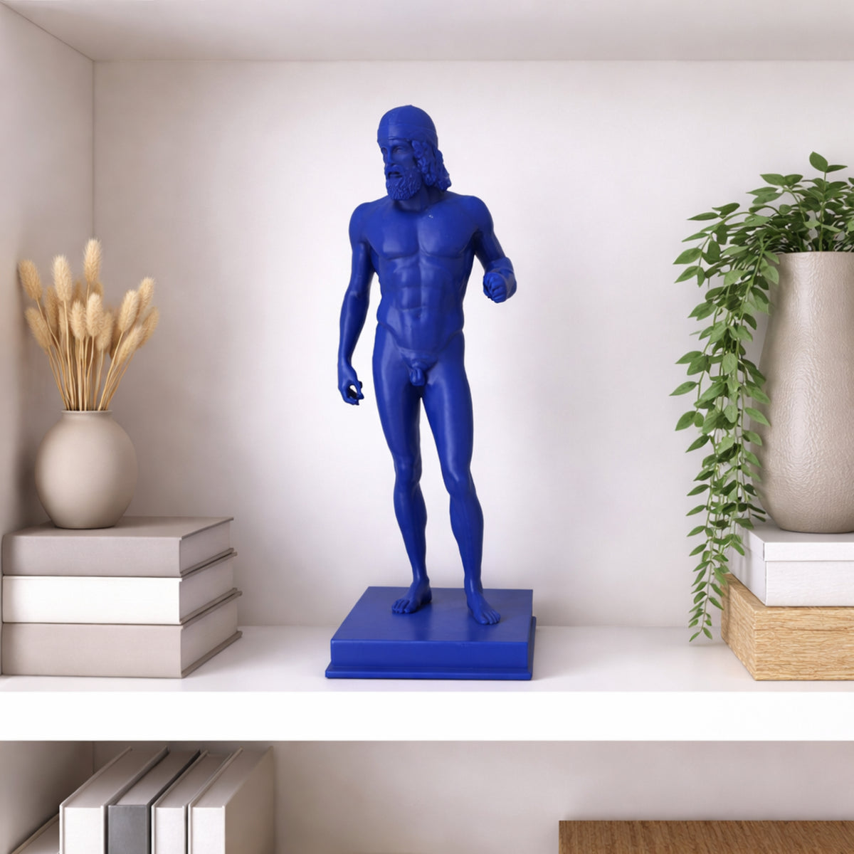 Riproduzione di un Bronzo di Riace in PLA blu su una mensola, tra libri e vasi con piante.