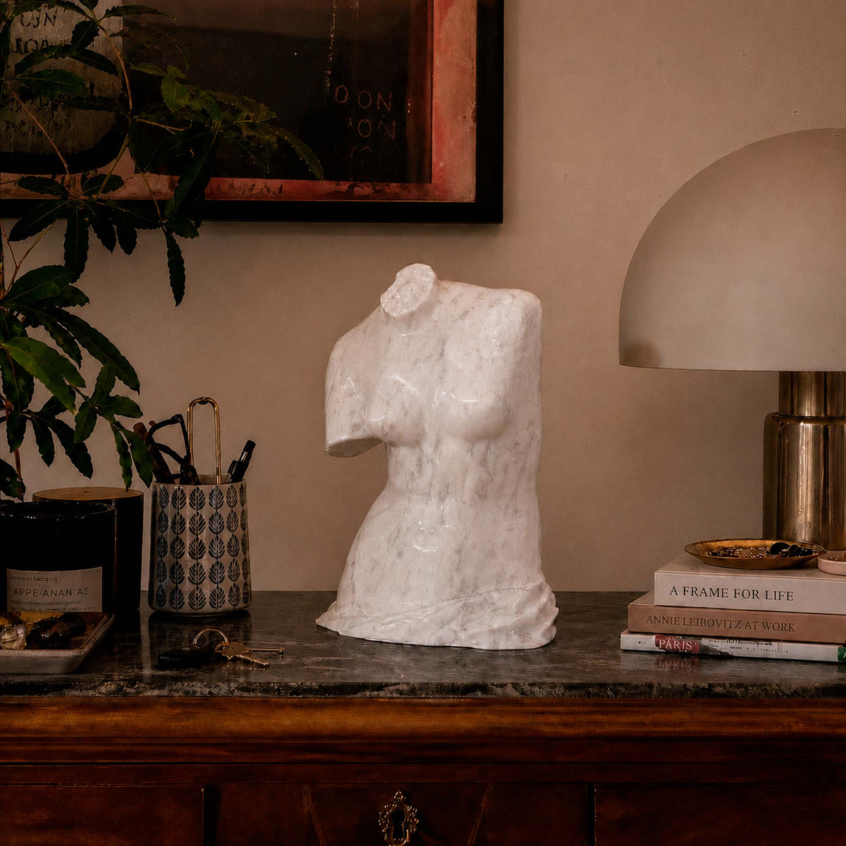 Torso della Venere di Milo in marmo di Carrara su una consolle accanto a una lampada.