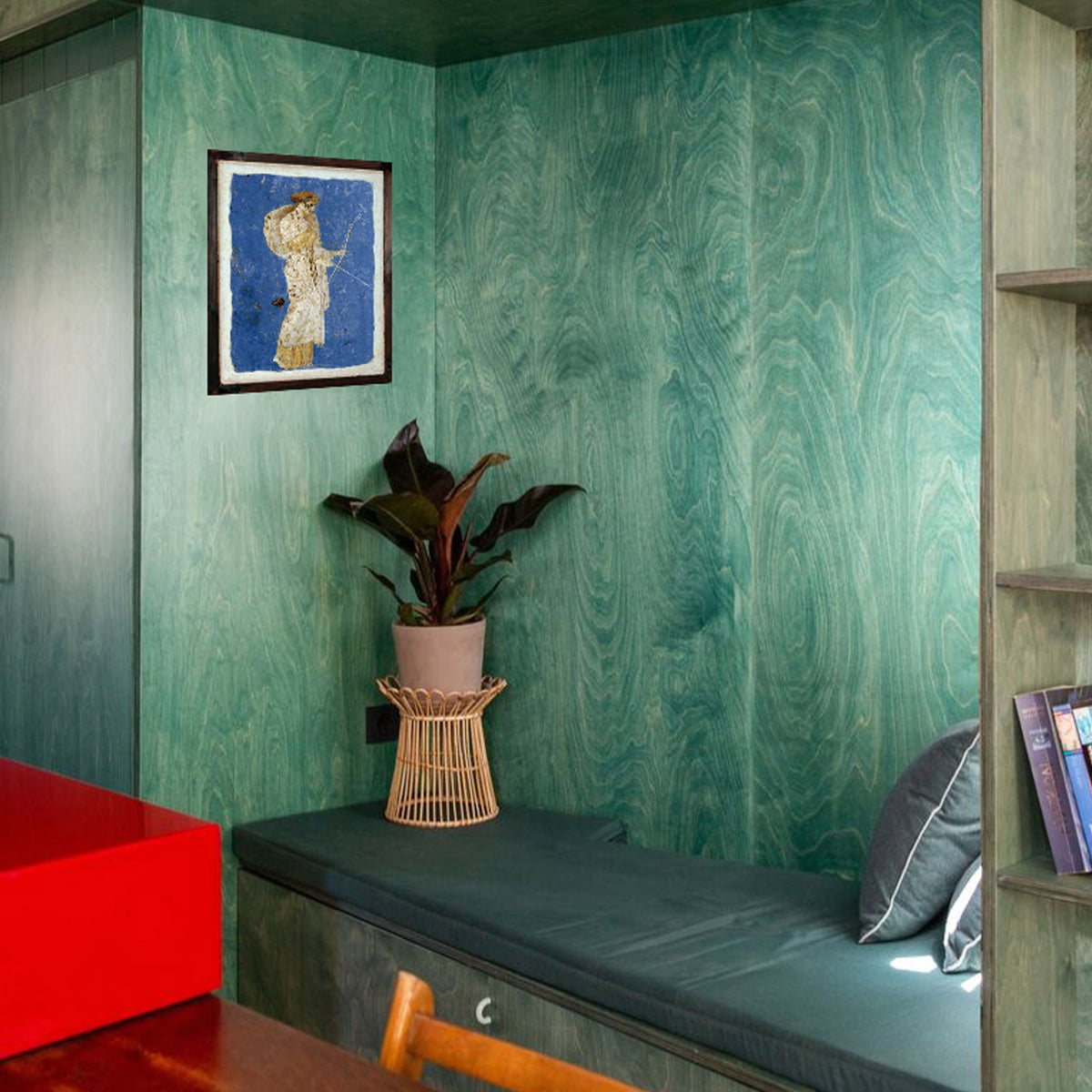 Affresco di Diana Cacciatrice in cornice, appeso a una parete verde sopra una panca con cuscini.