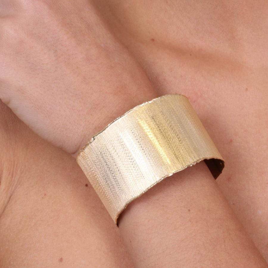 Bracciale rigido in argento placcato oro con superficie graffiata, indossato al polso