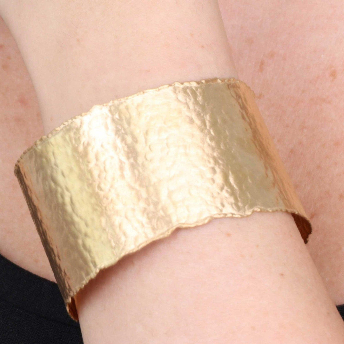 Bracciale rigido in argento placcato oro con superficie sabbiata, indossato al polso