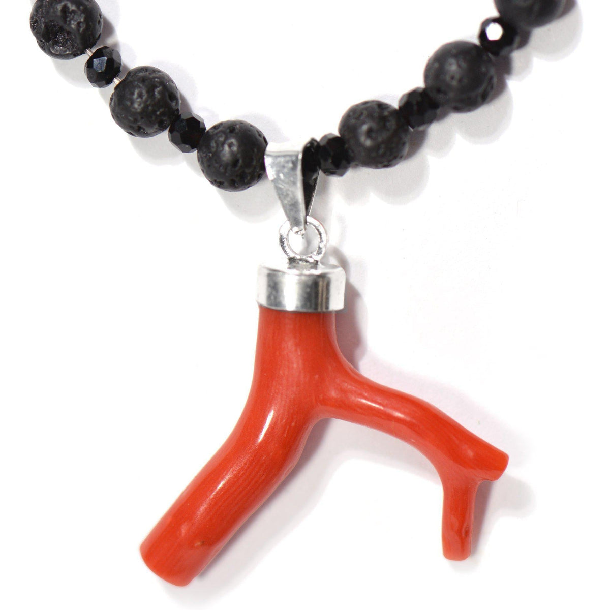 Dettaglio del ramo di corallo rosso con montatura in argento, pietra lavica e onice