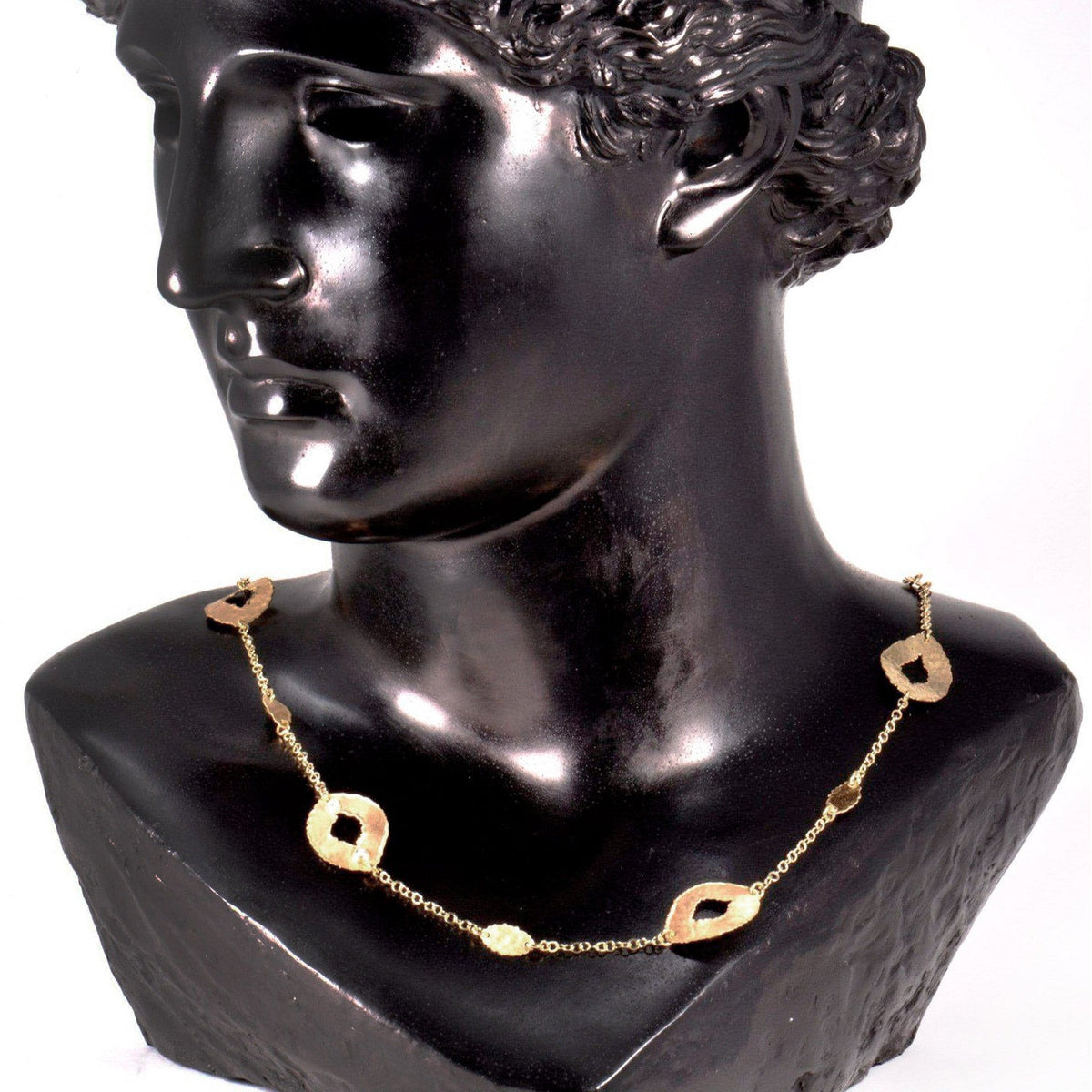 Collana stile schiava in argento dorato con elementi ovali traforati su un busto nero