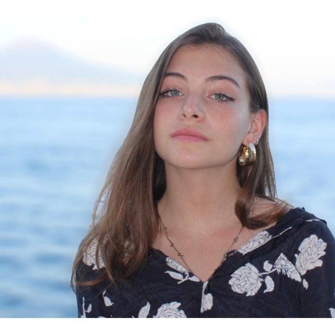 Orecchini in stile etrusco in argento placcato oro, indossati da una donna davanti al mare