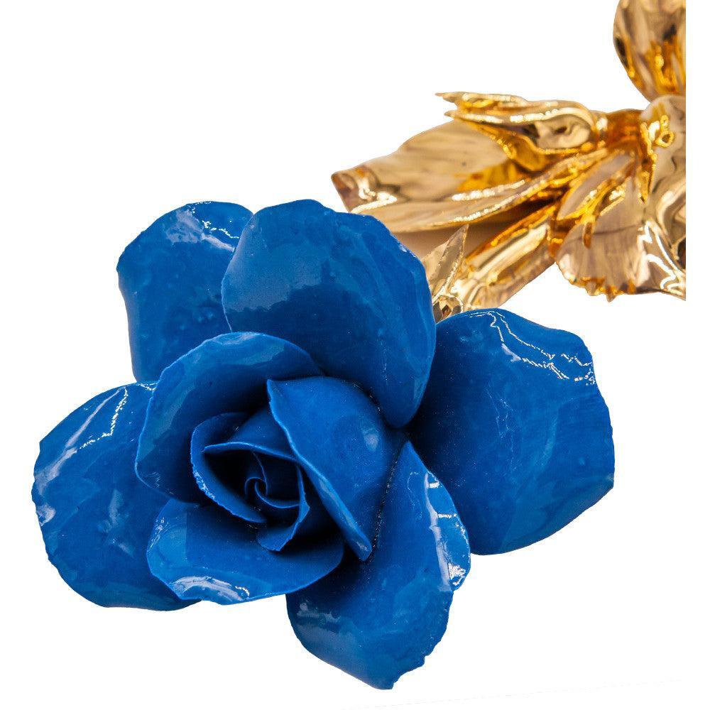 Dettaglio dei petali blu della rosa in porcellana di Capodimonte, con foglie dorate sullo sfondo.